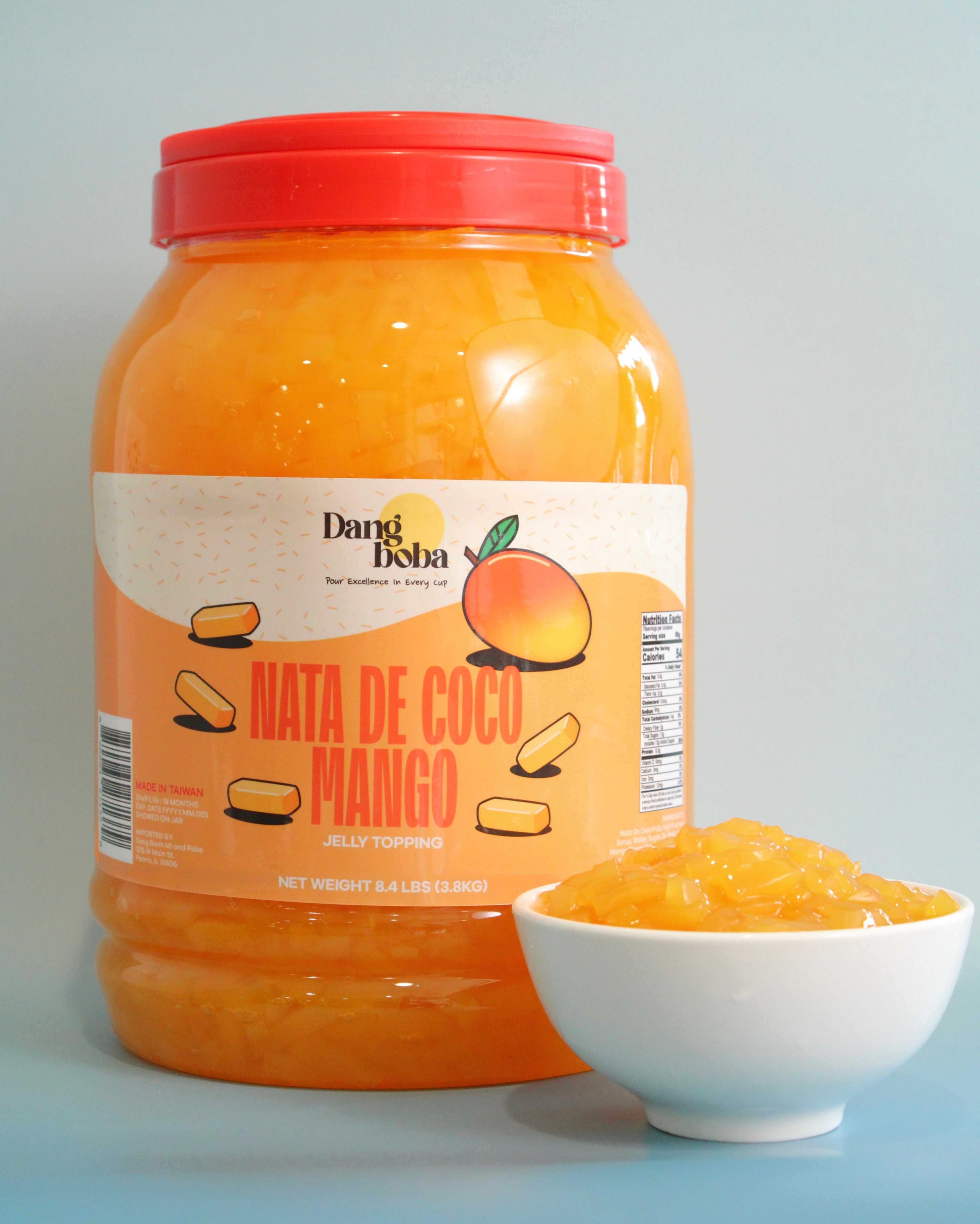 Jar of Dang Bisa Nata de Coco Mango with a bowl of the product on a light blue background
